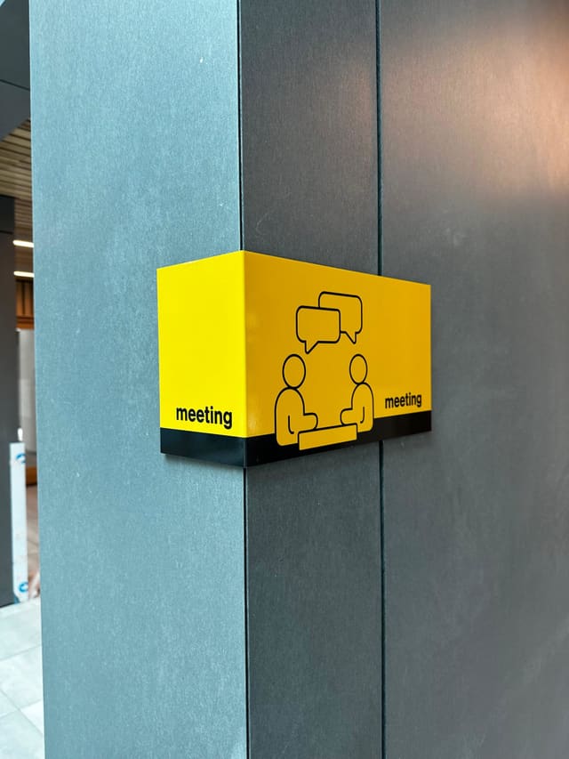 Geel hoekbord met pictogram dat een vergaderruimte aanwijst