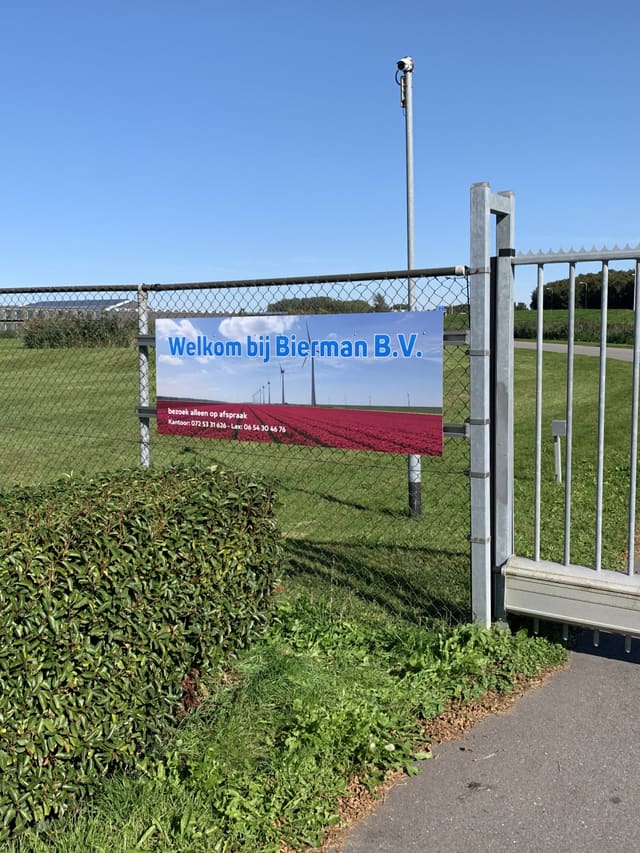 Spandoek met welkomsttekst aan een hek bij een bedrijf