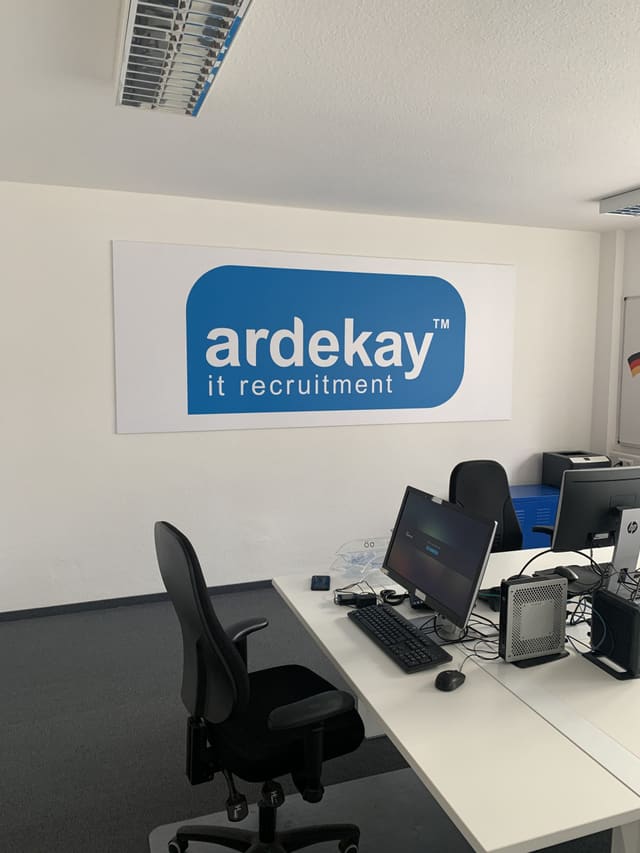 Wandbord met blauw logo boven een werkplek