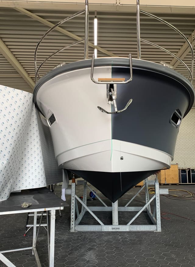 Boeg van een motorboot halverwege het wrappen: links nog wit, rechts al donkergrijs