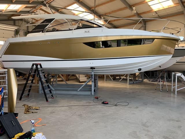Motorjacht met een goudkleurige rompwrap in de loods