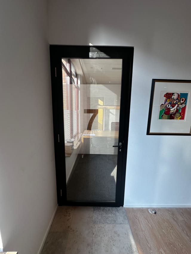Glazen deur met zwart kozijn, een groot cijfer en matte stroken