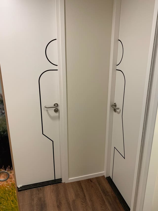Twee witte toiletdeuren met lijnfiguren van zwarte folie
