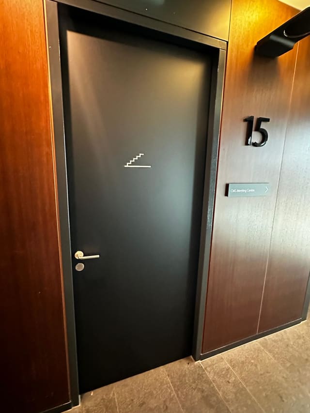 Zwart beplakte deur met een wit trappictogram, naast een houten wand met het cijfer 15