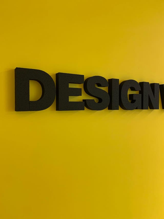 Zwarte 3D-letters op een felgele wand
