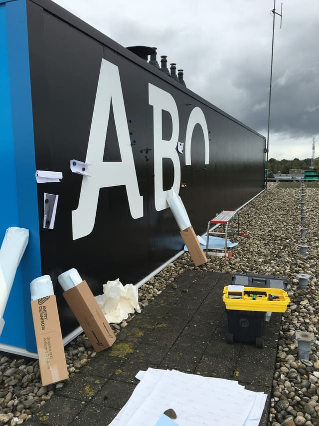 Grote witte letters worden op een zwarte gevel geplakt