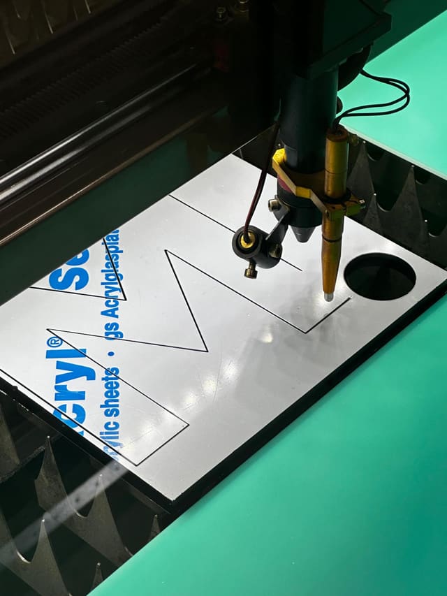 Lasersnijder snijdt letters uit een plaat acryl