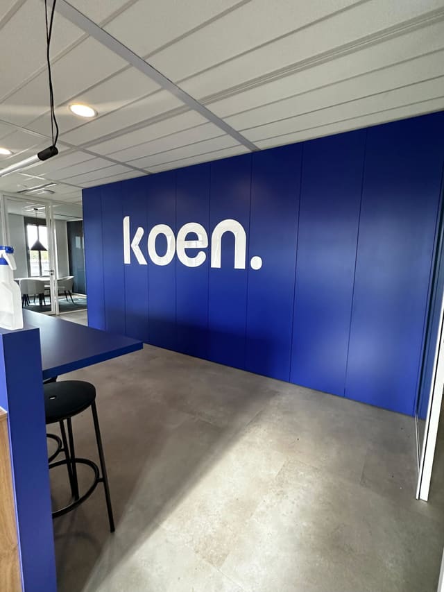 Wit logo op een donkerblauwe wand in een kantoorruimte