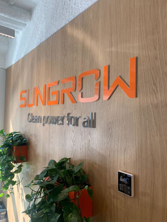Oranje logoletters met slogan op een houten wand in een kantoor