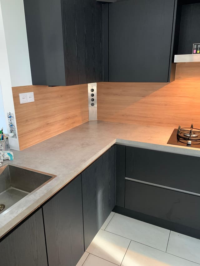 Zwarte hoekkeuken met een achterwand in houtlook