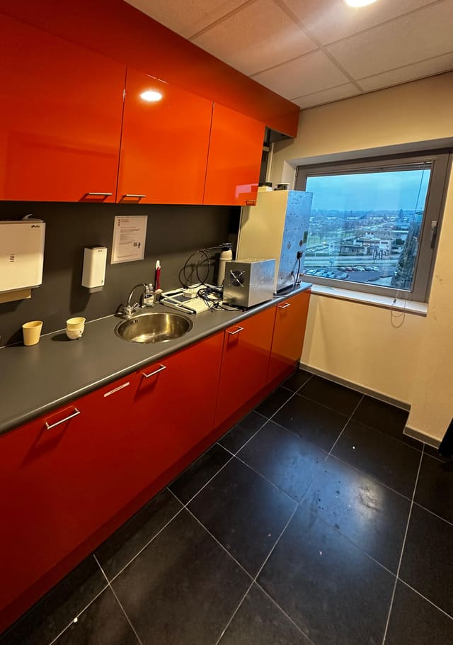 Kantoorpantry met oranje hoogglanskastjes vóór het wrappen