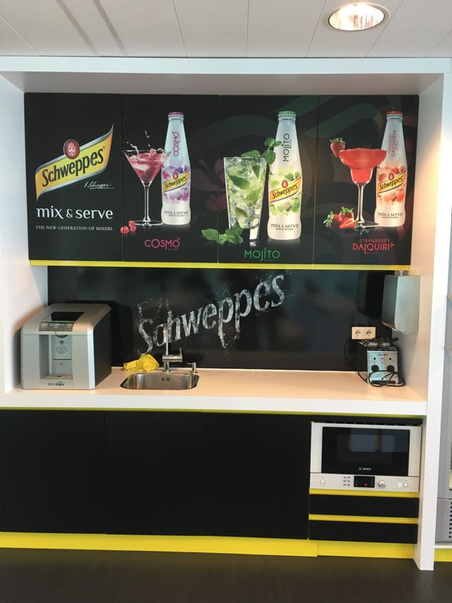Bedrijfspantry in geel en zwart met een merkprint boven het aanrecht