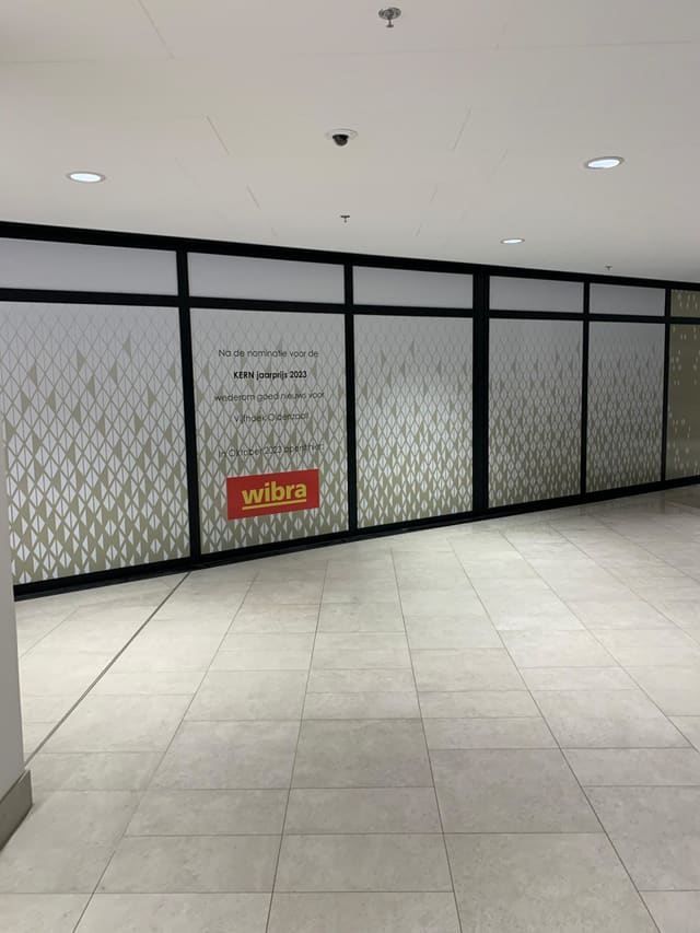 Glazen wanden met decoratieve folie en logo in een winkelcentrum