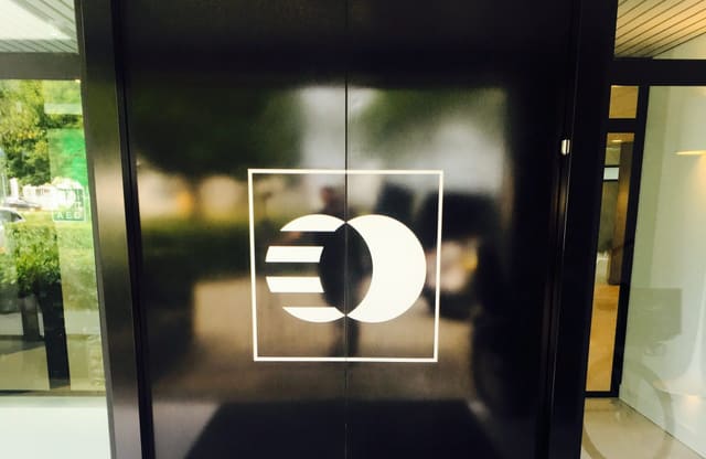 Zwarte glazen deur met een wit logo van folie
