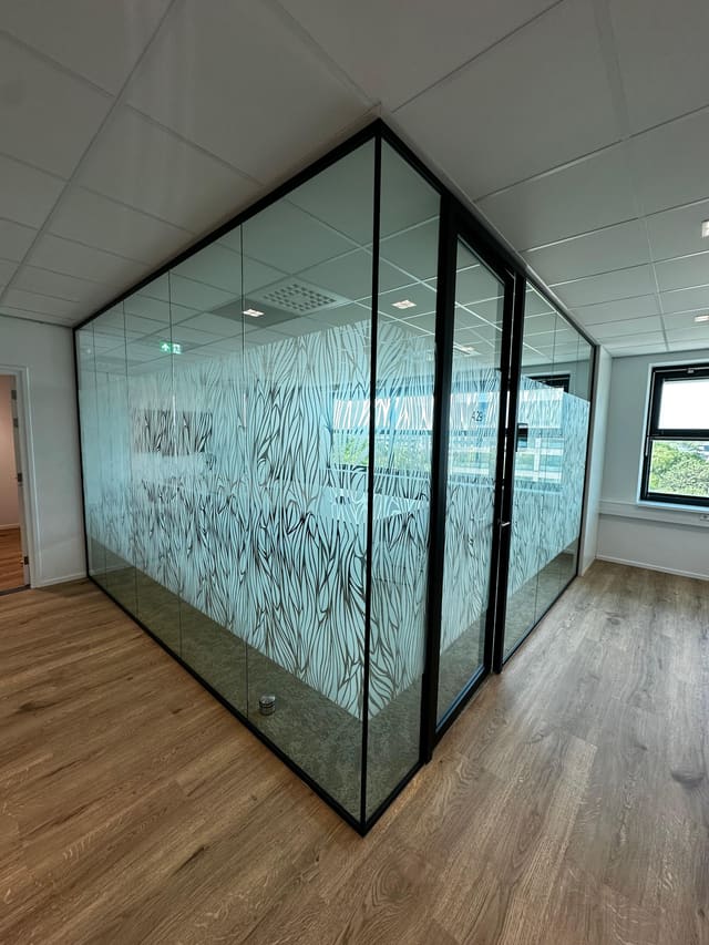 Glazen vergaderkamer met folie in een patroon van grassprieten