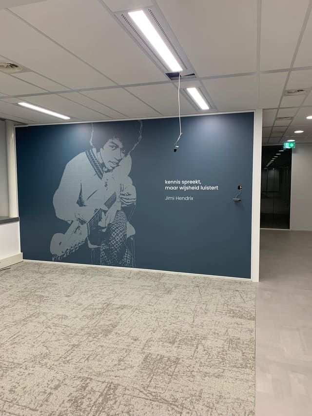 Donkerblauwe wand met een lijntekening van een gitarist en een citaat