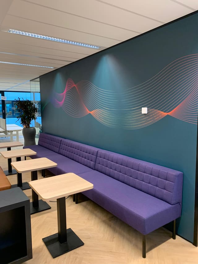 Petrolblauwe wand met gekleurde golflijnen boven een paarse bank