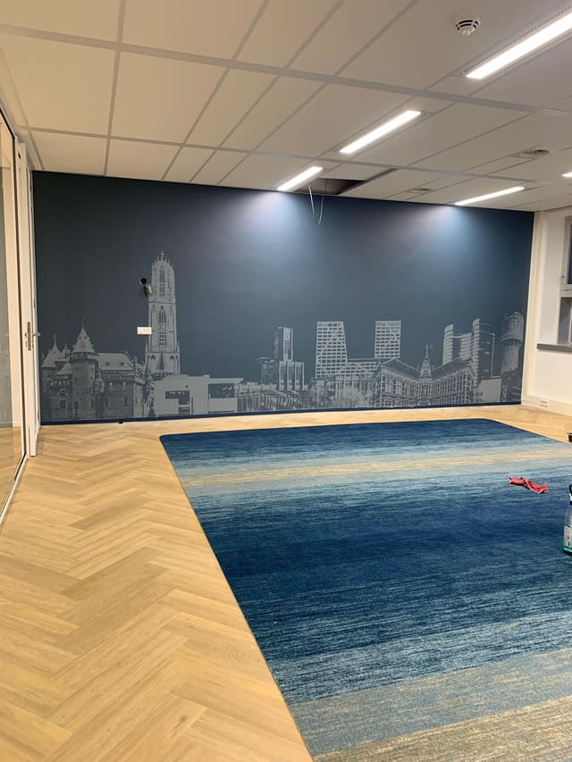Brede donkerblauwe wand met een lichte afbeelding van een stadsskyline