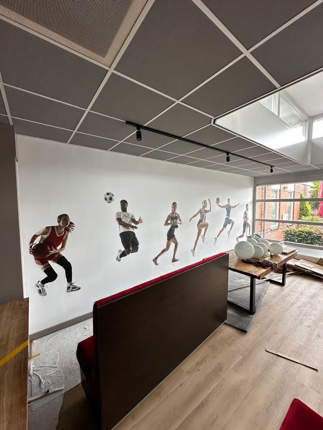 Witte wand met losse figuren van sporters in actie