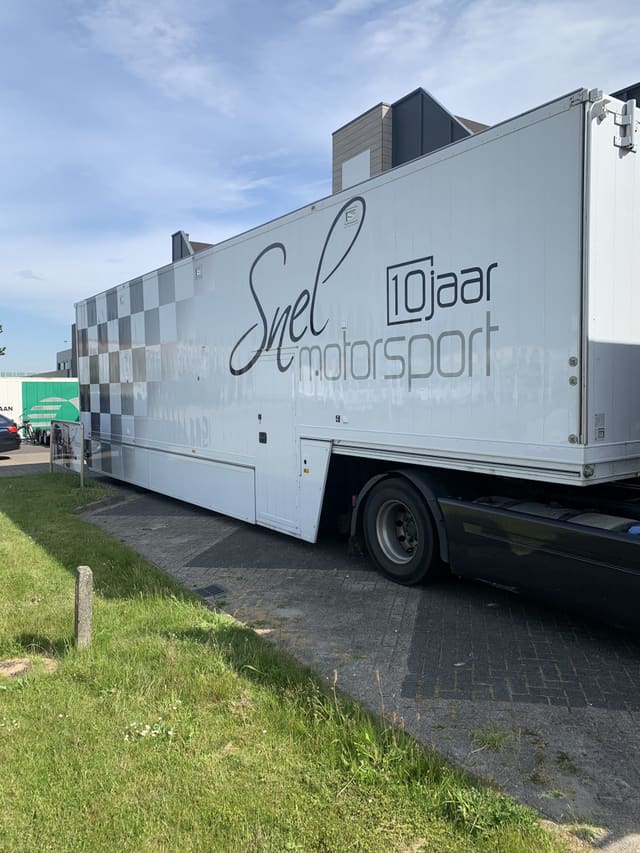 Vrachtwagenoplegger met grote belettering voor een motorsportteam