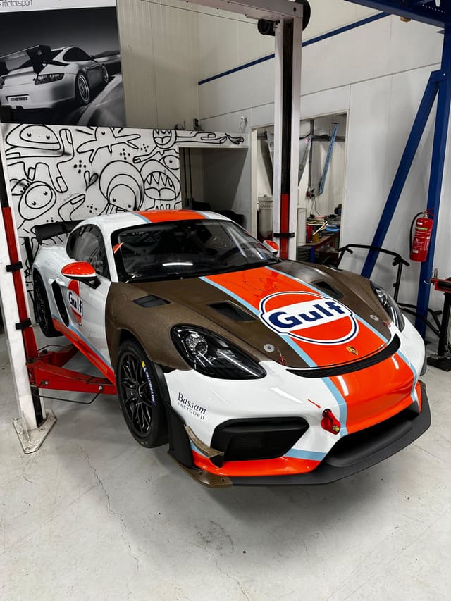Porsche met oranje-blauwe Gulf-livery van folie in de werkplaats