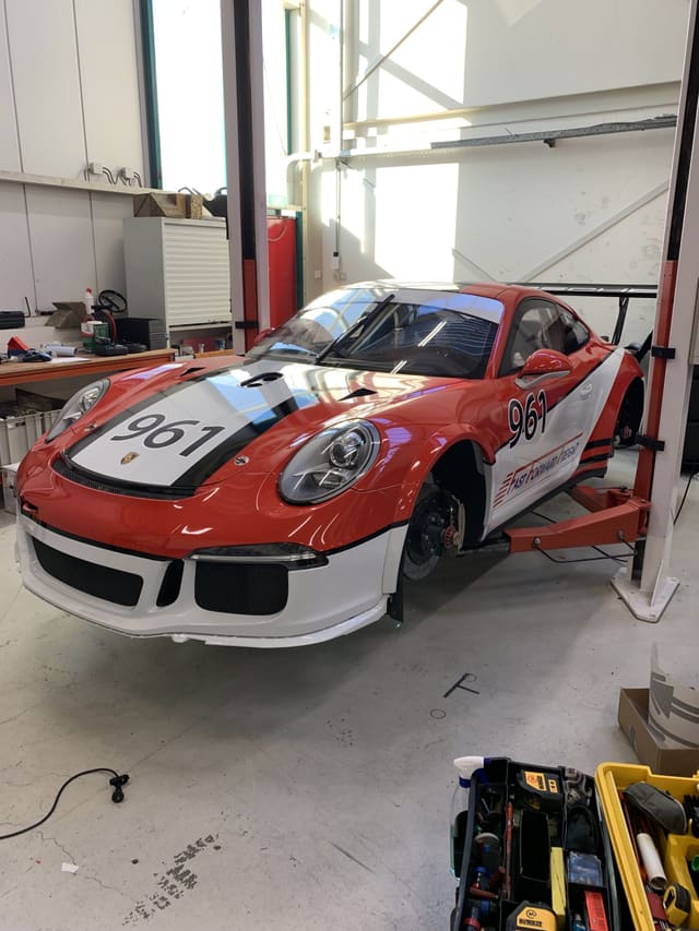 Porsche met rood-witte racebelettering en startnummers