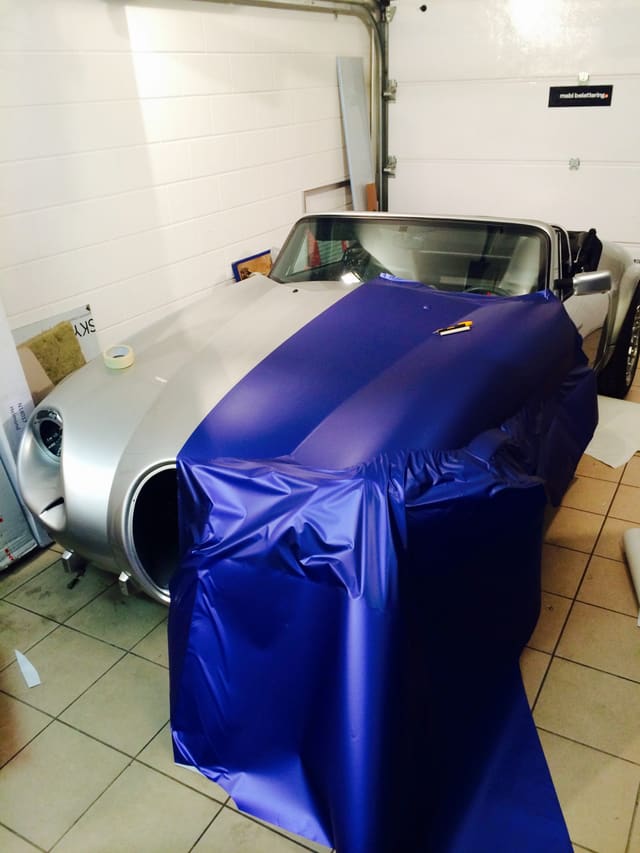Klassieke sportwagen wordt in blauwe wrapfolie gezet